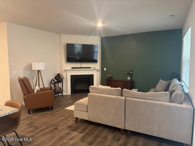 living room featuring a fireplace, visible vents, and dark wood-type flooring