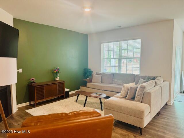 living area featuring a fireplace, wood finished floors, and baseboards