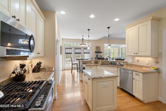 2906 Legends Dr, Southport, NC 28461 - kitchen with appliances with stainless steel finishes, backsplash, a peninsula, light stone countertops, and light wood finished floors