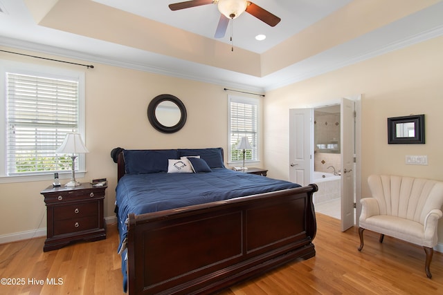 2906 Legends Dr, Southport, NC 28461 - bedroom featuring multiple windows, a raised ceiling, light wood-style floors, crown molding, and ensuite bathroom
