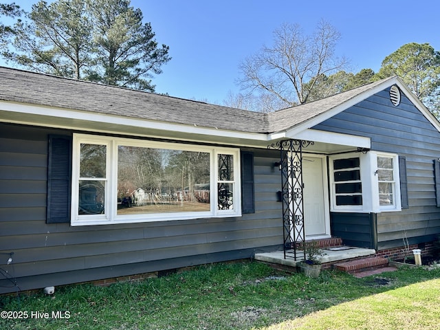 view of front of property with roof with shingles and a front yard