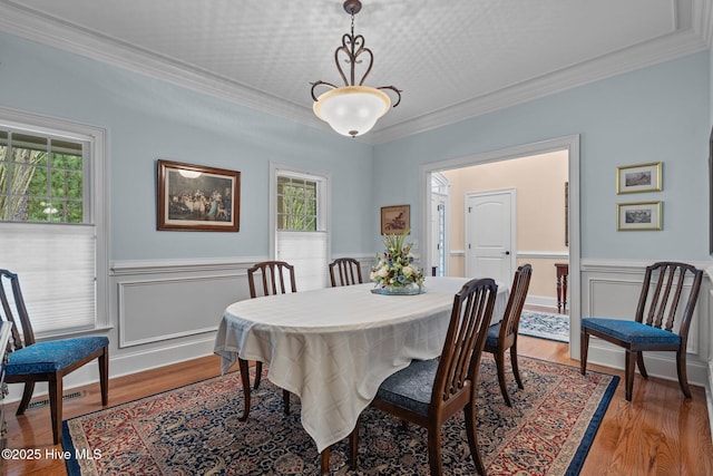 dining room featuring plenty of natural light, light wood-type flooring, a wainscoted wall, and ornamental molding