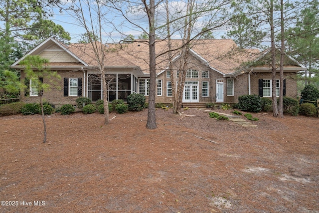view of front of home with brick siding, a sunroom, and crawl space