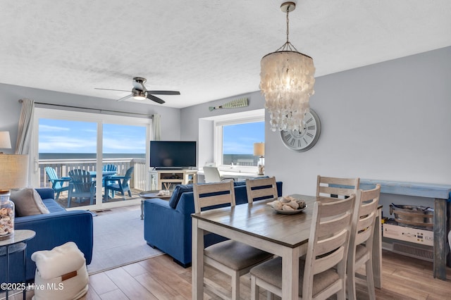 dining area with a textured ceiling, wood finished floors, and ceiling fan with notable chandelier