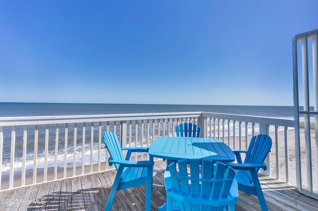 wooden deck with outdoor dining space, a beach view, and a water view