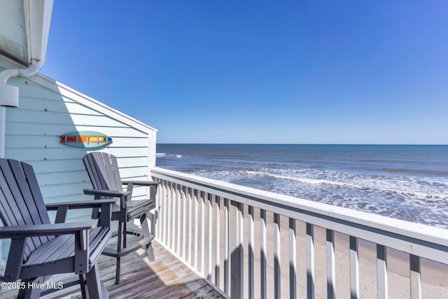 balcony with a water view and a view of the beach