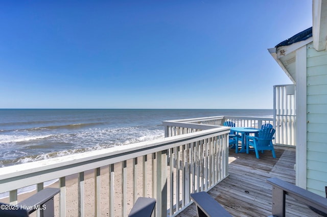 wooden terrace with a water view and a view of the beach