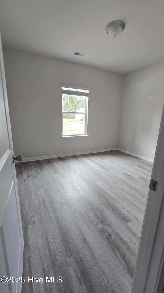 spare room with visible vents, baseboards, and wood finished floors