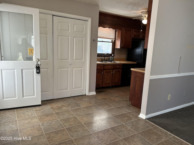 kitchen with a ceiling fan, baseboards, a sink, light countertops, and a textured ceiling