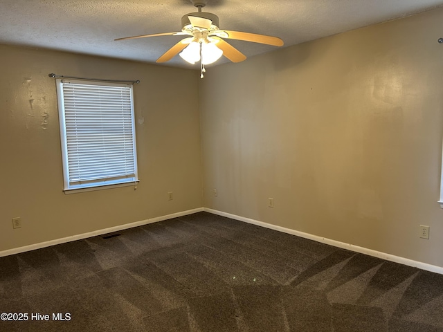 empty room with dark colored carpet, visible vents, baseboards, and a textured ceiling