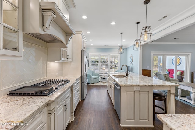 kitchen featuring custom range hood, open floor plan, appliances with stainless steel finishes, and a sink