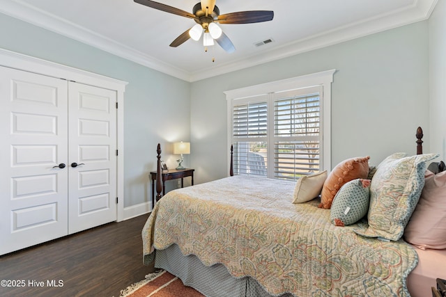 bedroom with visible vents, dark wood-type flooring, baseboards, ornamental molding, and a closet