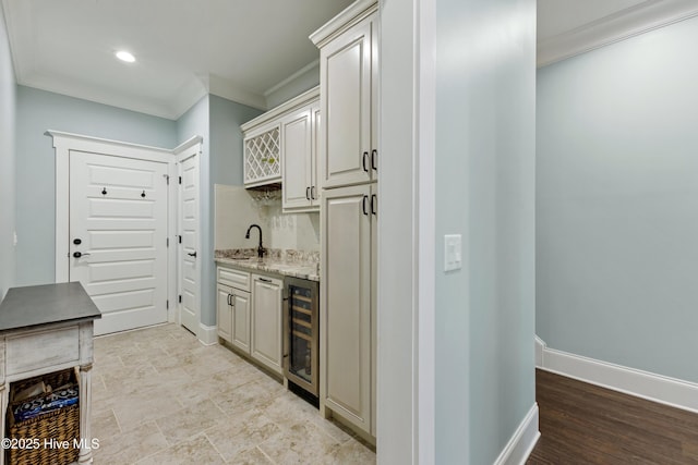 bar with beverage cooler, a sink, crown molding, indoor wet bar, and baseboards