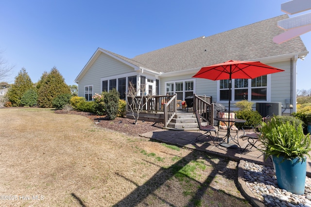 back of property featuring a patio, roof with shingles, a wooden deck, central air condition unit, and a lawn