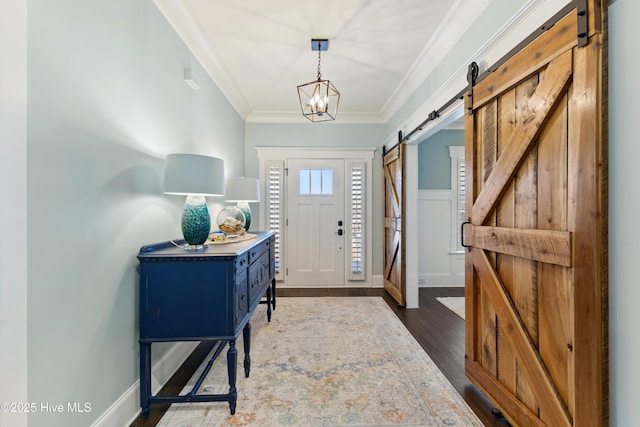 entryway with baseboards, crown molding, a barn door, and dark wood-style flooring