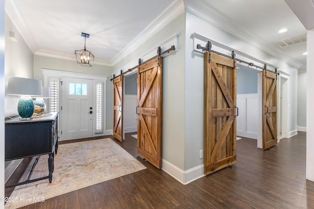 foyer entrance featuring visible vents, ornamental molding, wood finished floors, a barn door, and baseboards