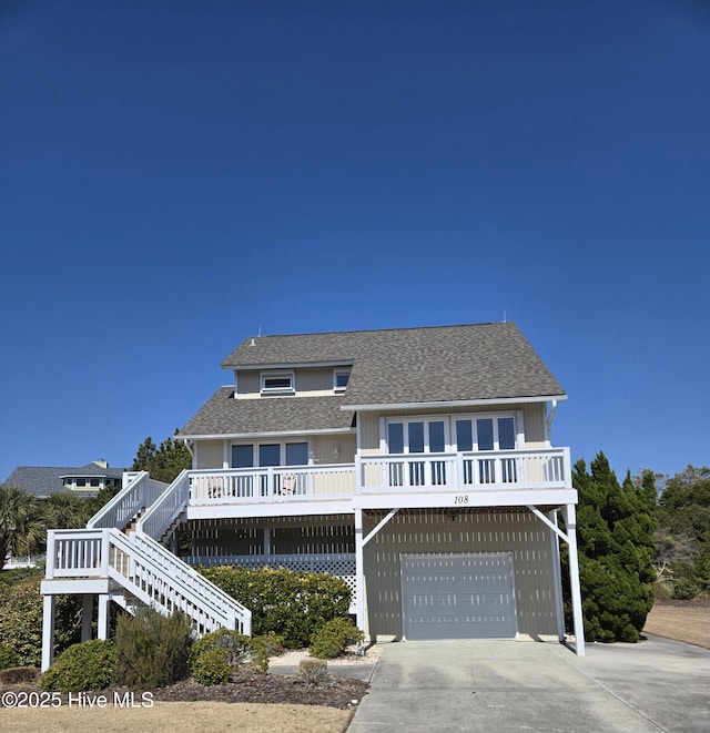 view of front of house with stairway, roof with shingles, a porch, an attached garage, and concrete driveway