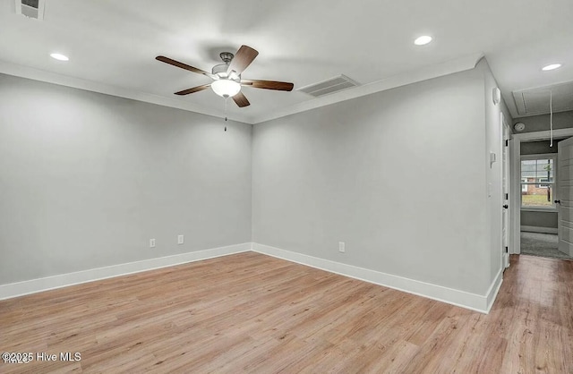 spare room featuring light wood finished floors, visible vents, attic access, a ceiling fan, and baseboards