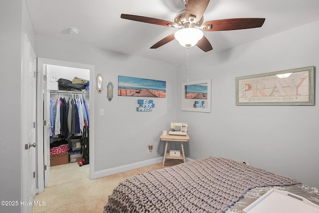 bedroom featuring a walk in closet, baseboards, ceiling fan, light colored carpet, and a closet