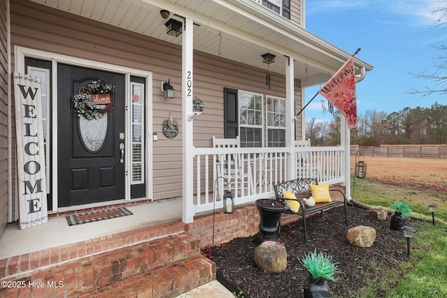 doorway to property featuring fence and covered porch