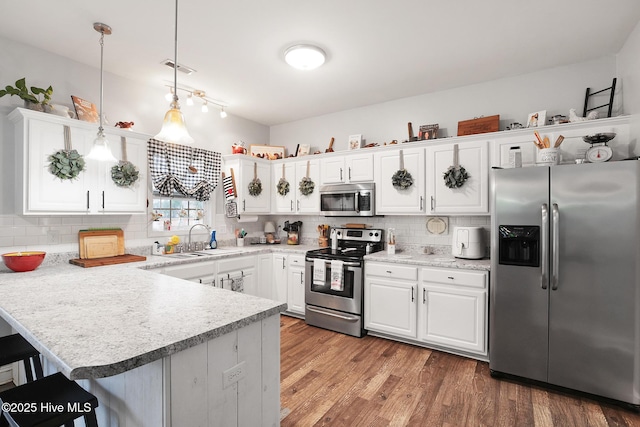 kitchen featuring white cabinetry, stainless steel appliances, a peninsula, light wood finished floors, and light countertops