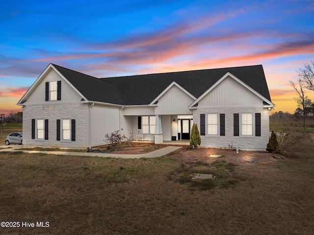 view of front of home featuring a porch, stone siding, and a lawn