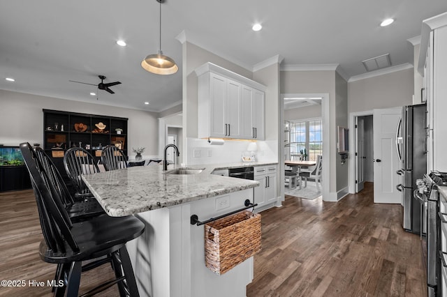 kitchen featuring light stone counters, dark wood-style floors, appliances with stainless steel finishes, a sink, and a peninsula