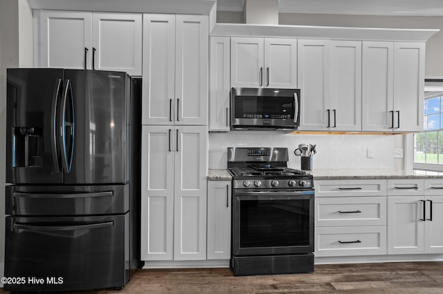 kitchen featuring light stone counters, appliances with stainless steel finishes, dark wood finished floors, and decorative backsplash