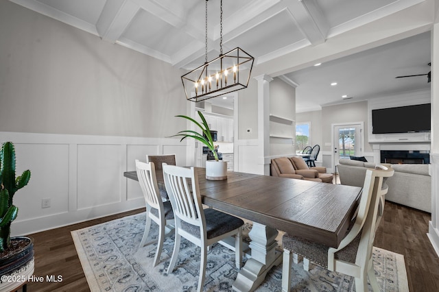 dining area featuring dark wood-style floors, a decorative wall, coffered ceiling, beamed ceiling, and a lit fireplace