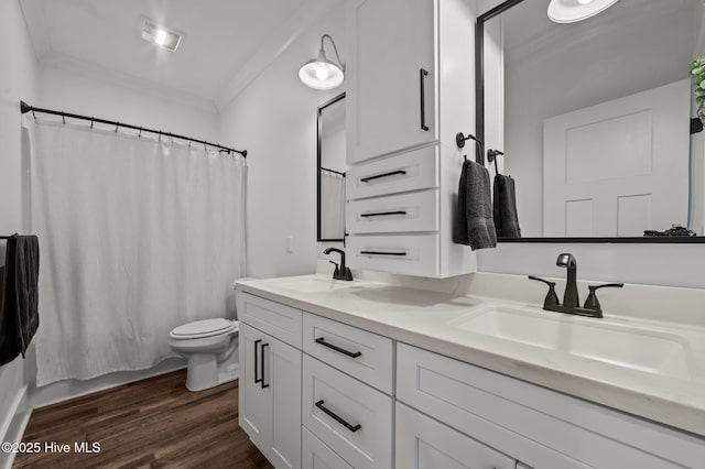 bathroom with ornamental molding, a sink, toilet, and wood finished floors