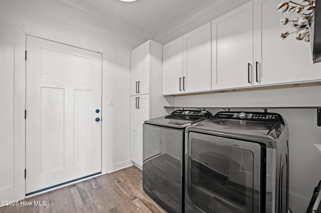 laundry room featuring washing machine and dryer, cabinet space, and light wood-style flooring