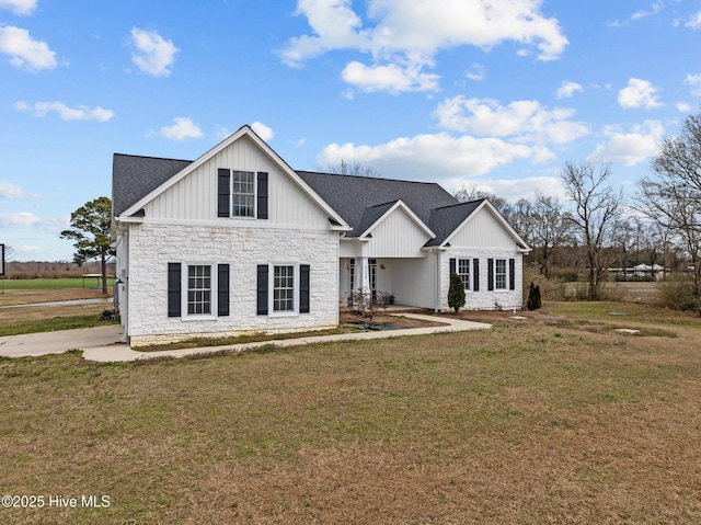 view of front of property with stone siding, a shingled roof, board and batten siding, and a front yard