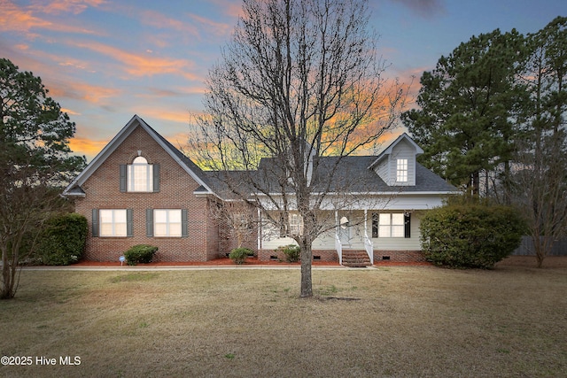 view of front of house featuring crawl space, a porch, brick siding, and a yard