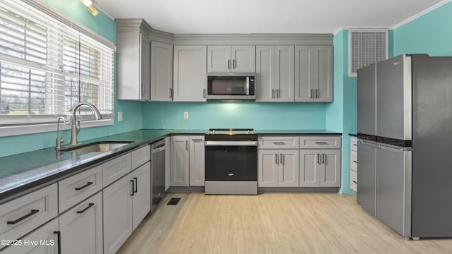 13596 Hobbton Hwy, Newton Grove, NC 28366 - kitchen featuring appliances with stainless steel finishes, a sink, gray cabinets, light wood finished floors, and ornamental molding