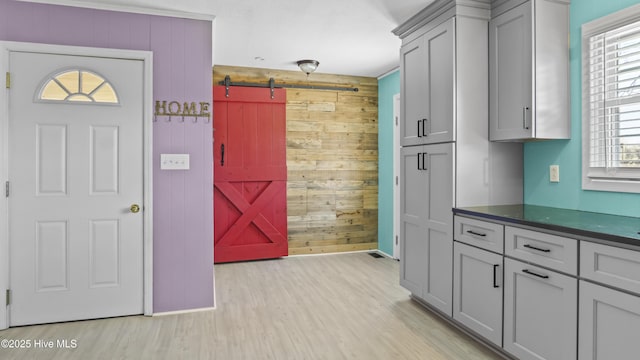 13596 Hobbton Hwy, Newton Grove, NC 28366 - kitchen featuring a barn door, wooden walls, dark countertops, gray cabinetry, and light wood-style floors