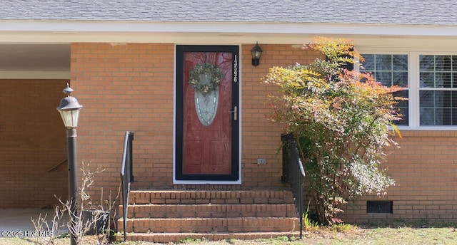 property entrance featuring crawl space, brick siding, and roof with shingles