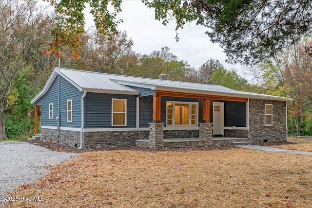 view of front of home featuring metal roof, stone siding, crawl space, and covered porch