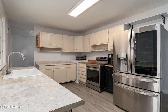 kitchen featuring a sink, stainless steel appliances, light wood finished floors, and light countertops