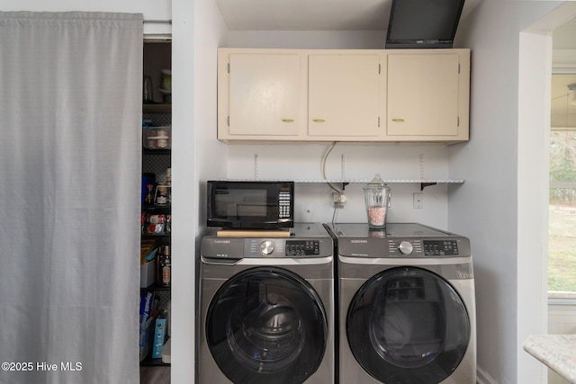 clothes washing area featuring cabinet space and washing machine and dryer