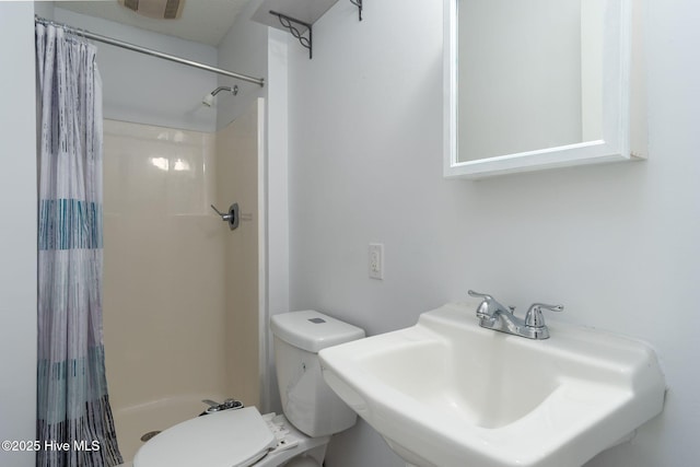 bathroom featuring toilet, a shower with shower curtain, and a sink