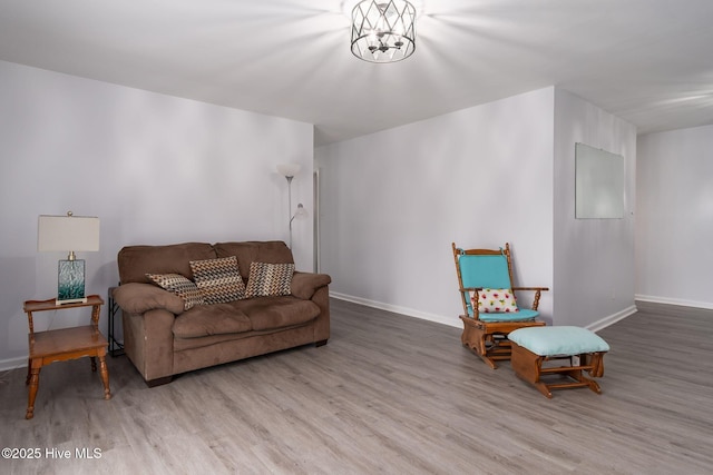 living area featuring a chandelier, baseboards, and wood finished floors