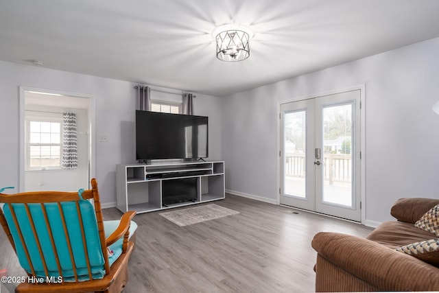 living area with a healthy amount of sunlight, french doors, baseboards, and wood finished floors