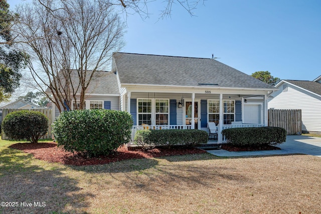 view of front facade with fence, a porch, a front lawn, and a shingled roof