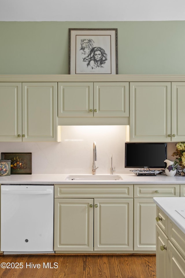 kitchen featuring dishwasher, cream cabinets, light countertops, and a sink