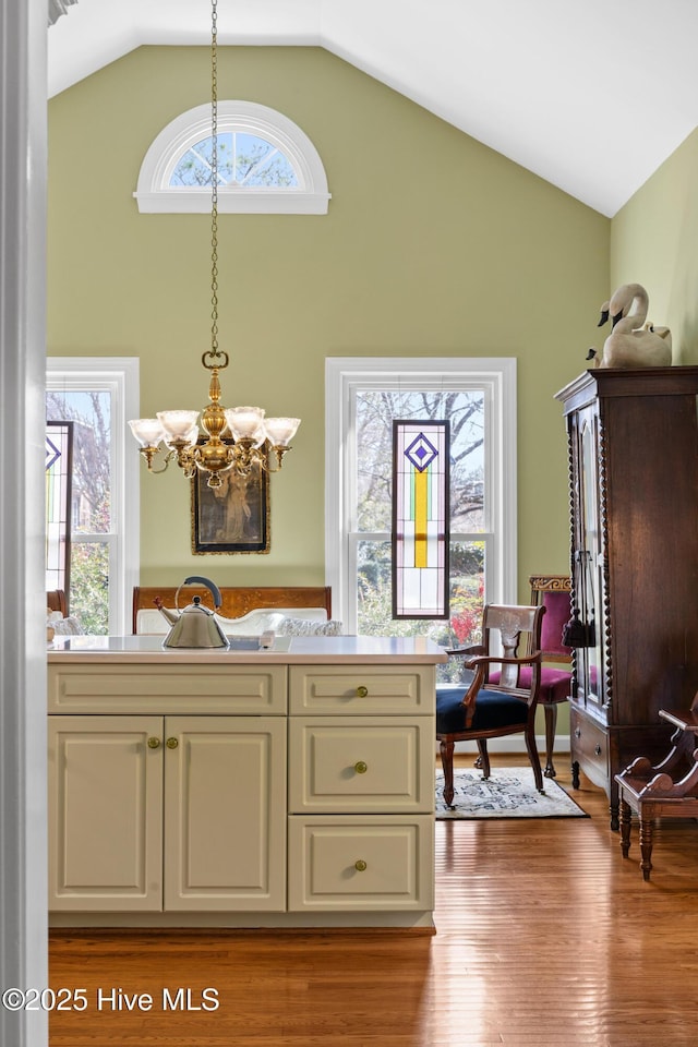 interior space with a notable chandelier, light wood-style floors, pendant lighting, and high vaulted ceiling