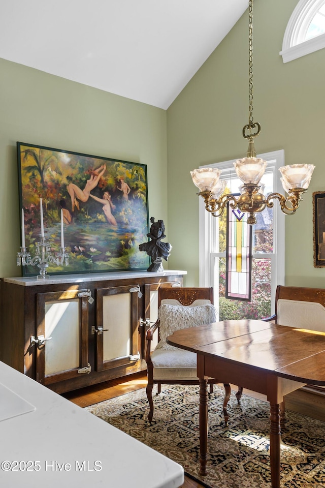 dining room featuring a notable chandelier, wood finished floors, and vaulted ceiling