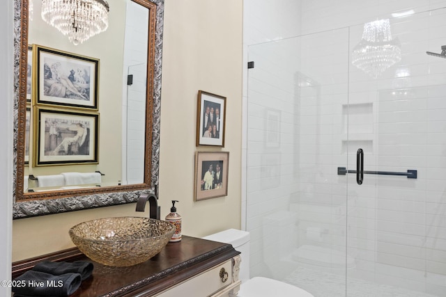 bathroom featuring a notable chandelier, a stall shower, vanity, and toilet