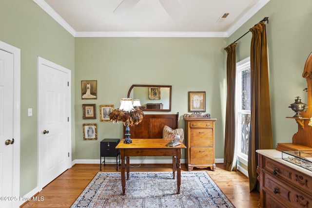 office space featuring light wood-type flooring, baseboards, visible vents, and crown molding