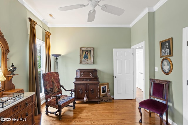 sitting room featuring visible vents, crown molding, light wood-type flooring, and baseboards