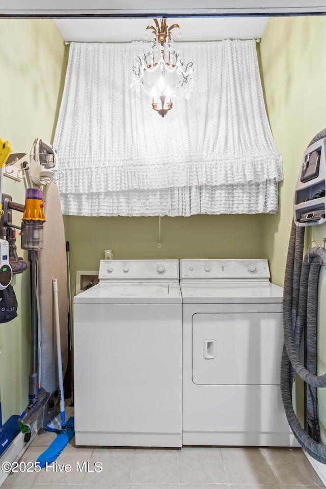 clothes washing area with an inviting chandelier, laundry area, light tile patterned floors, and washer and clothes dryer